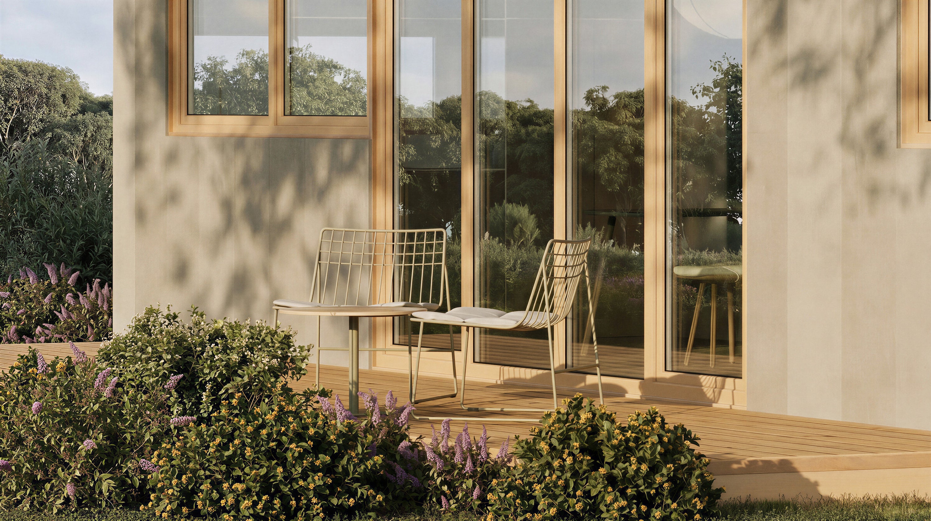Two metal chairs on a wooden deck with large windows and greenery in the background