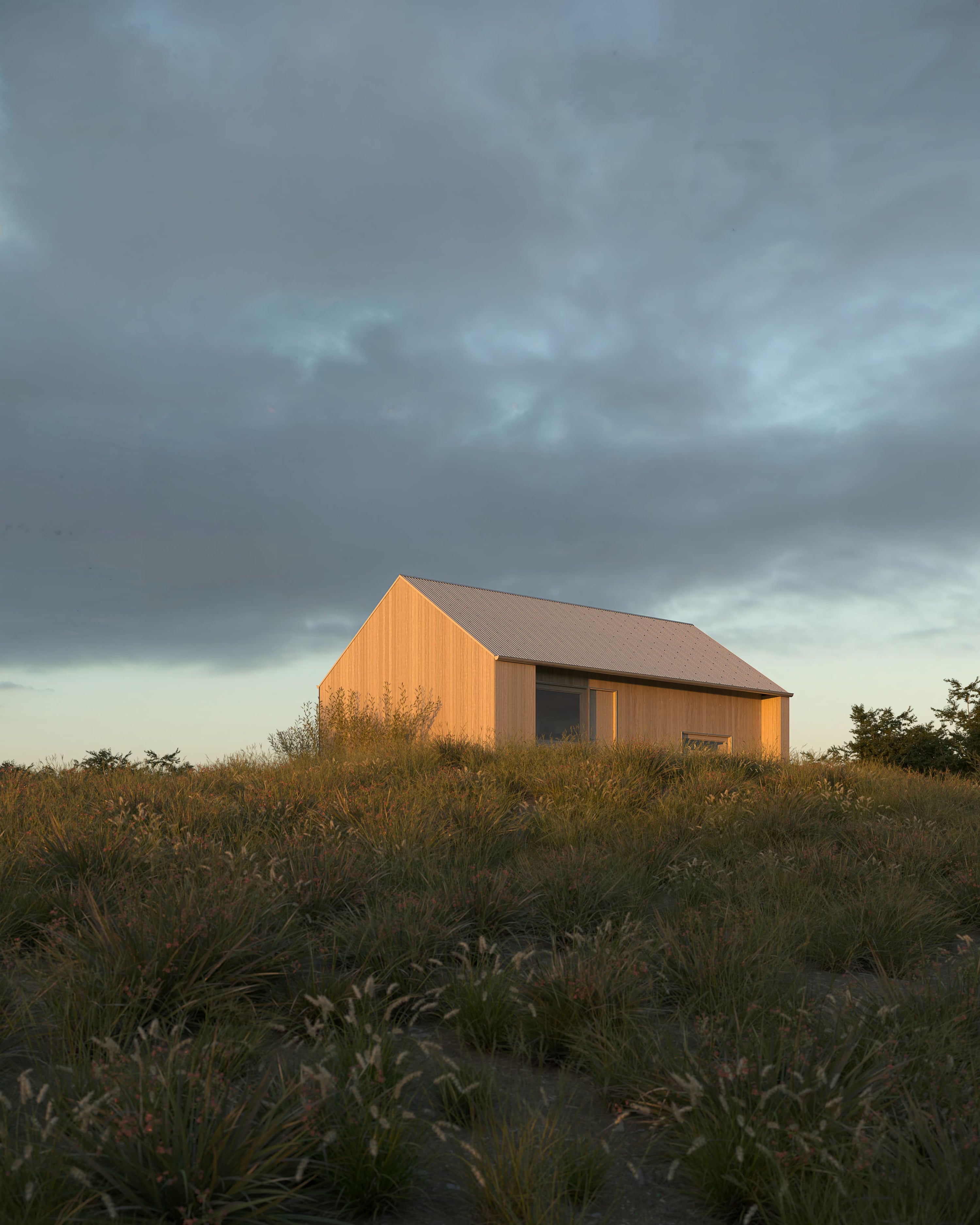 Wooden cabin in a field under a dark, stormy sky