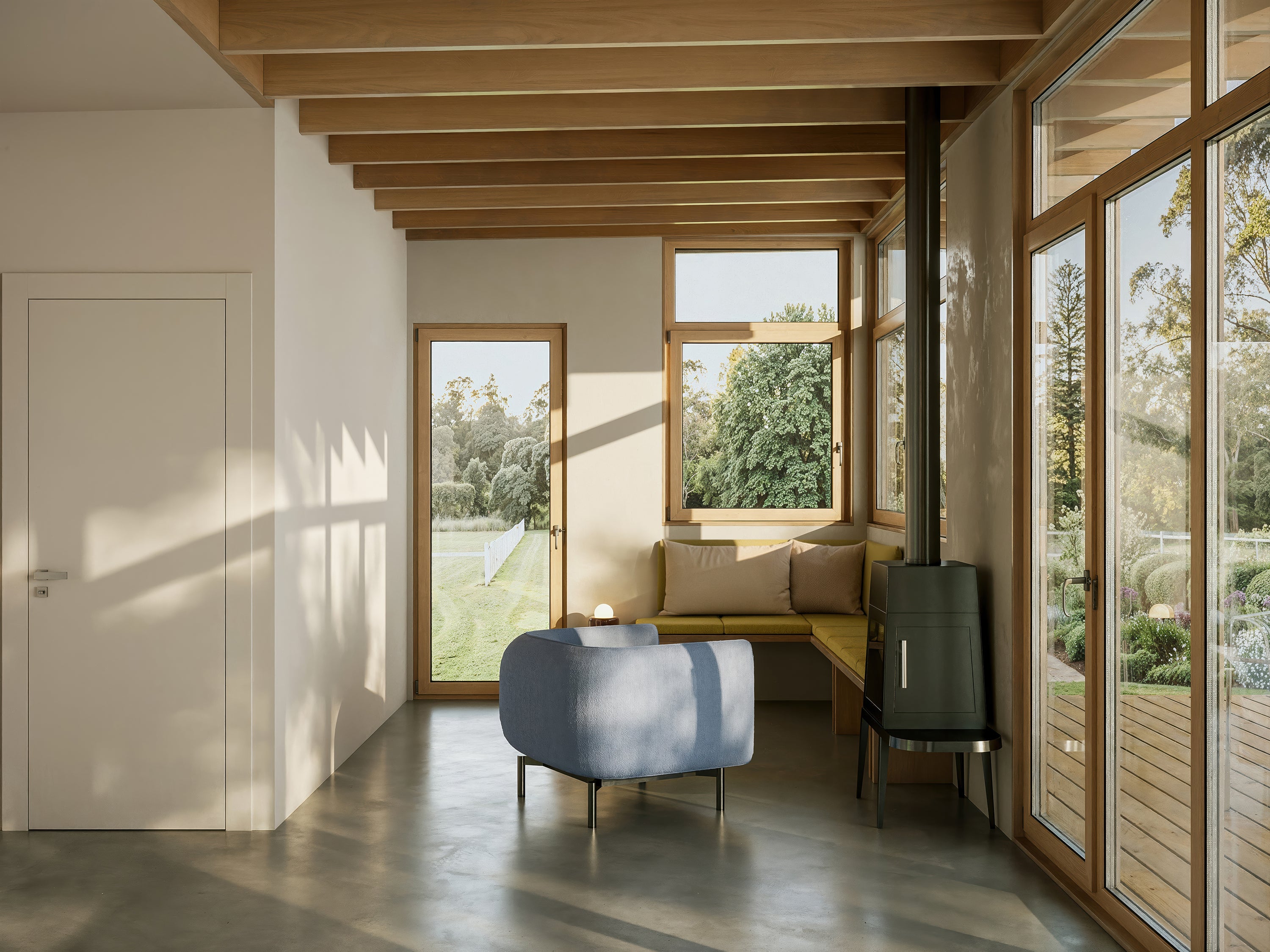 Modern living room with large windows, wooden ceiling, and a blue armchair.